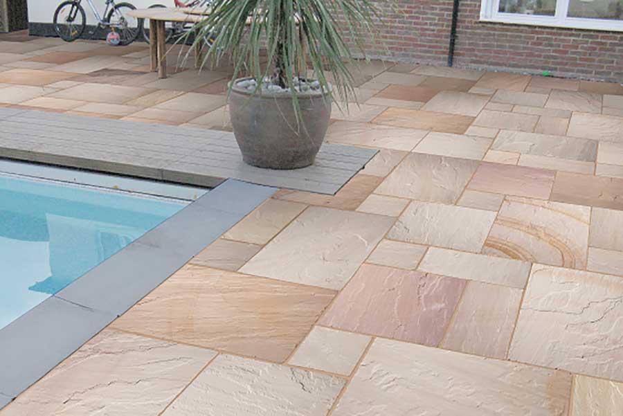 Stylish garden swimming pool surrounded by Global Stone Ravenna Indian Sandstone paving